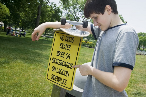 Boy with skateboard by sign